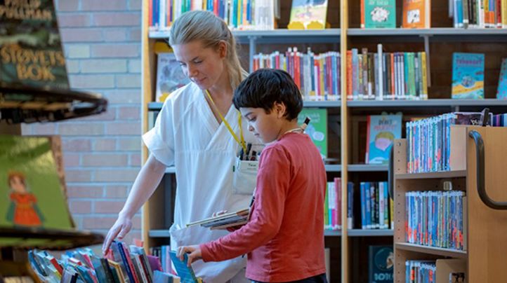 Bilde av elev og medisinsk ansatt som plukker ut bøker på biblioteket på Rikshospitalet